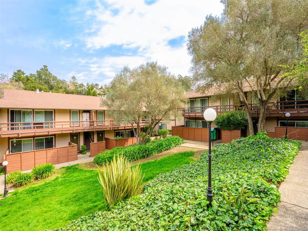 an exterior view of an apartment building with grass and trees