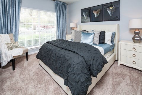 A bedroom with a large bed and a window with blinds.