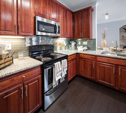 A kitchen with dark wood cabinets and a black stove top oven.