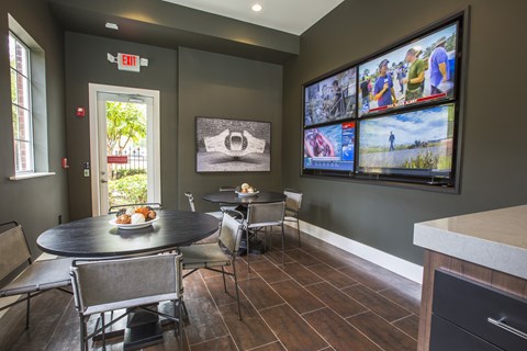 A dining room with a table set for two and a wall of television screens.