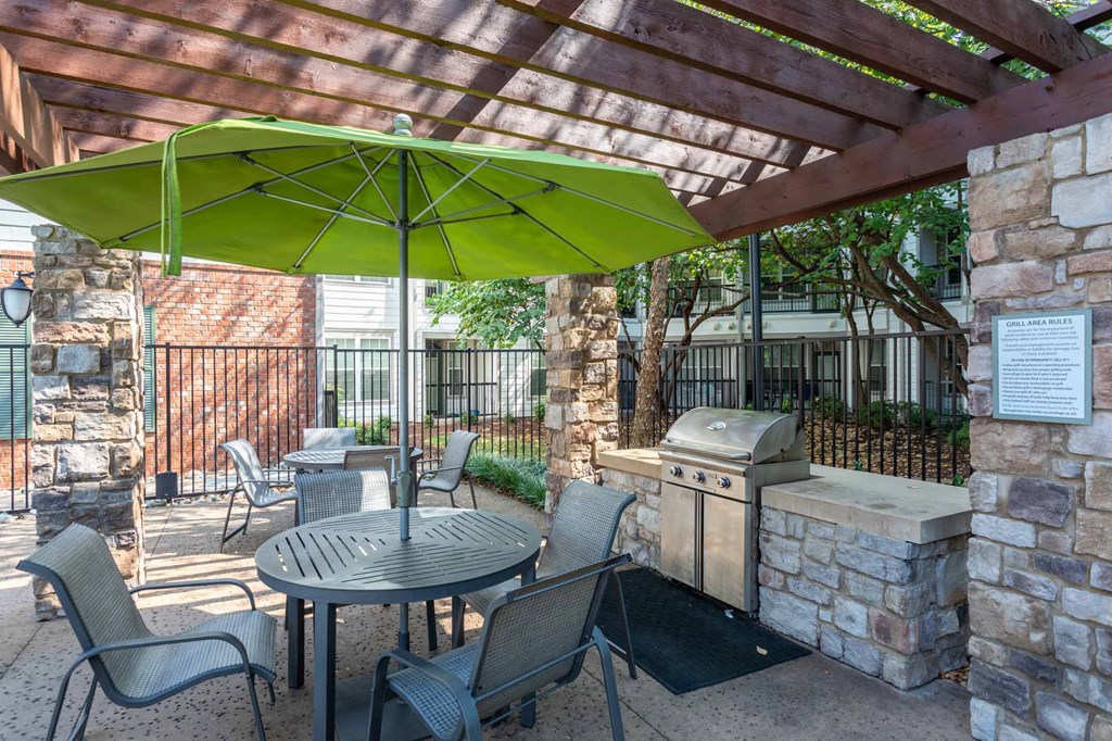 A patio with a table and chairs under a green umbrella.