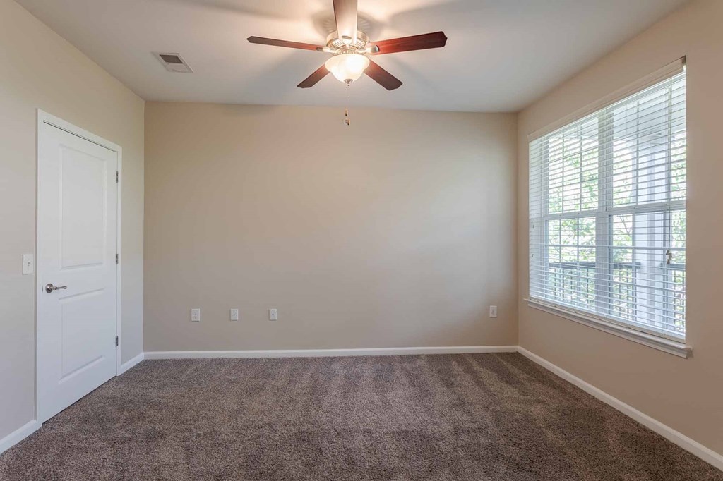 A bedroom with a ceiling fan and a window with blinds.