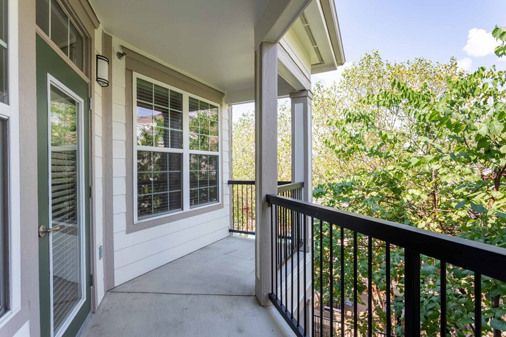 A balcony with a black railing and a view of trees.