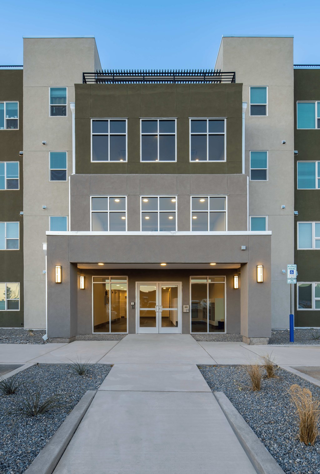 A modern apartment building with a flat roof and a large glass entrance.