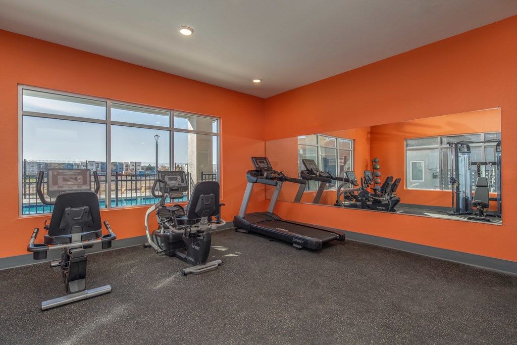 A gym with orange walls and a view of the city.