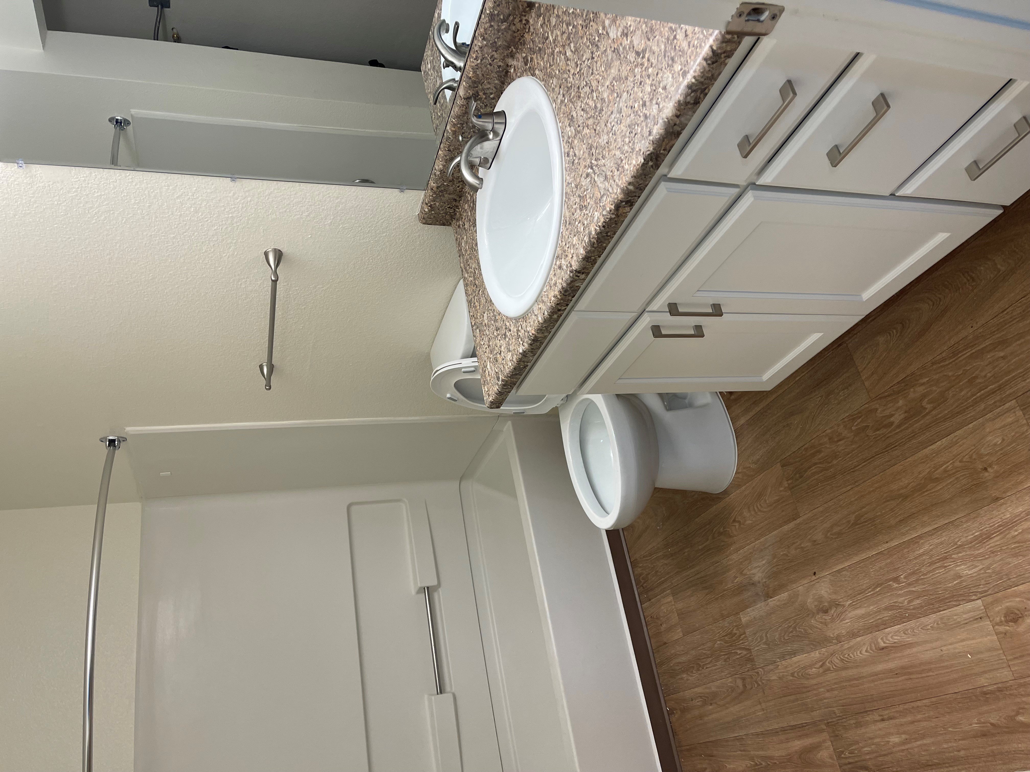 A white toilet with a white tank and a white shower curtain.