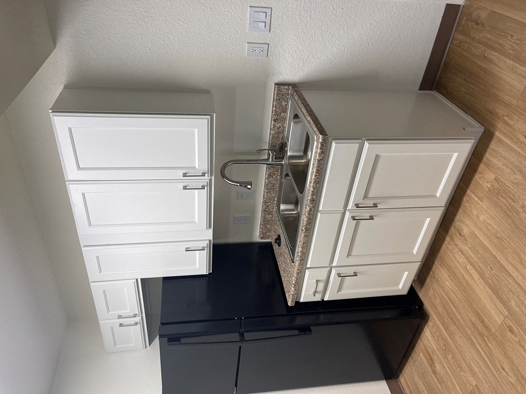 A kitchen with white cabinets and black countertops.