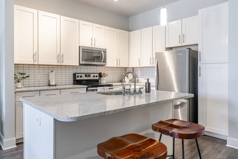 A kitchen with white cabinets and a marble countertop.