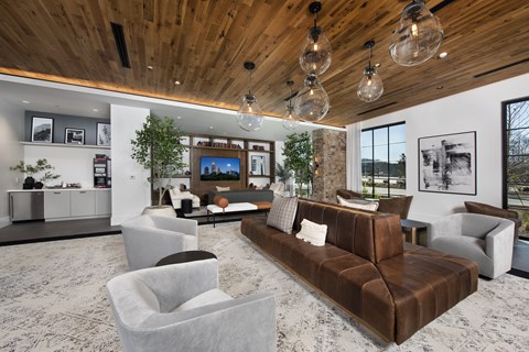 A modern living room with a brown leather couch and white chairs.