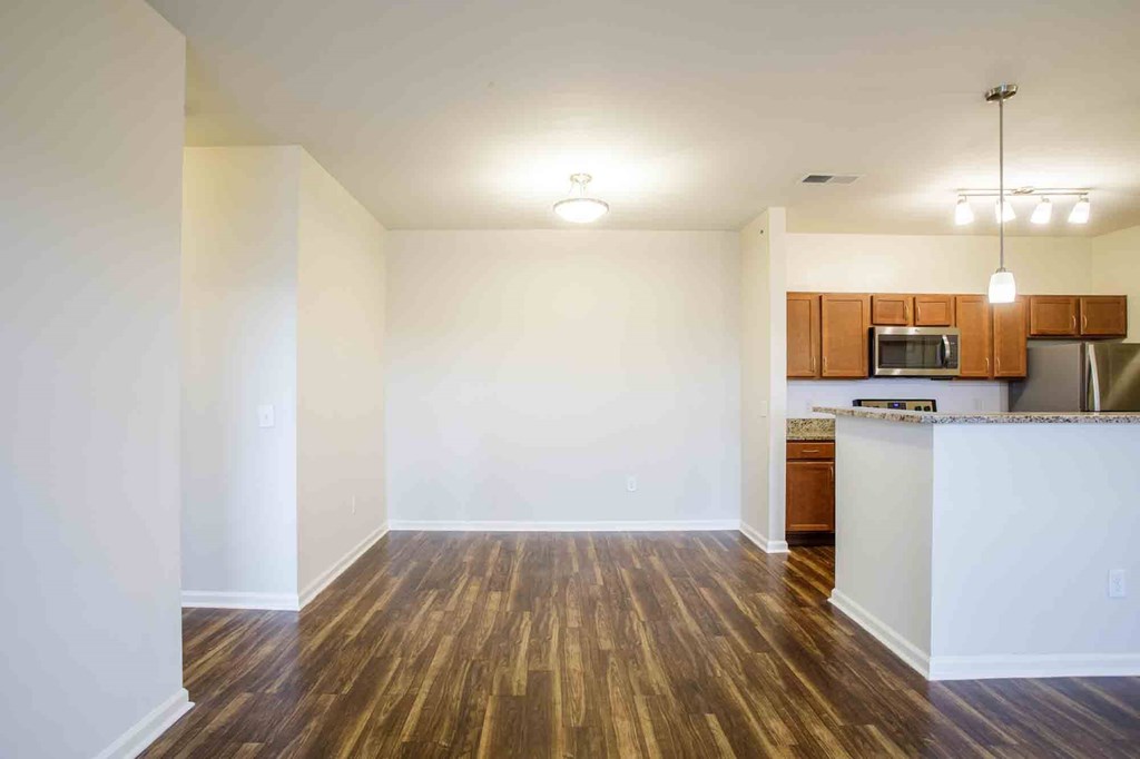Living room leading to dining room and kitchen with hardwood floors and overhead lighting.