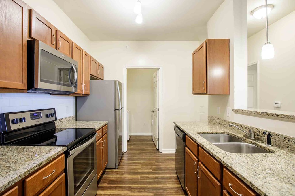 A kitchen with wooden cabinets and granite countertops with stainless steel appliances