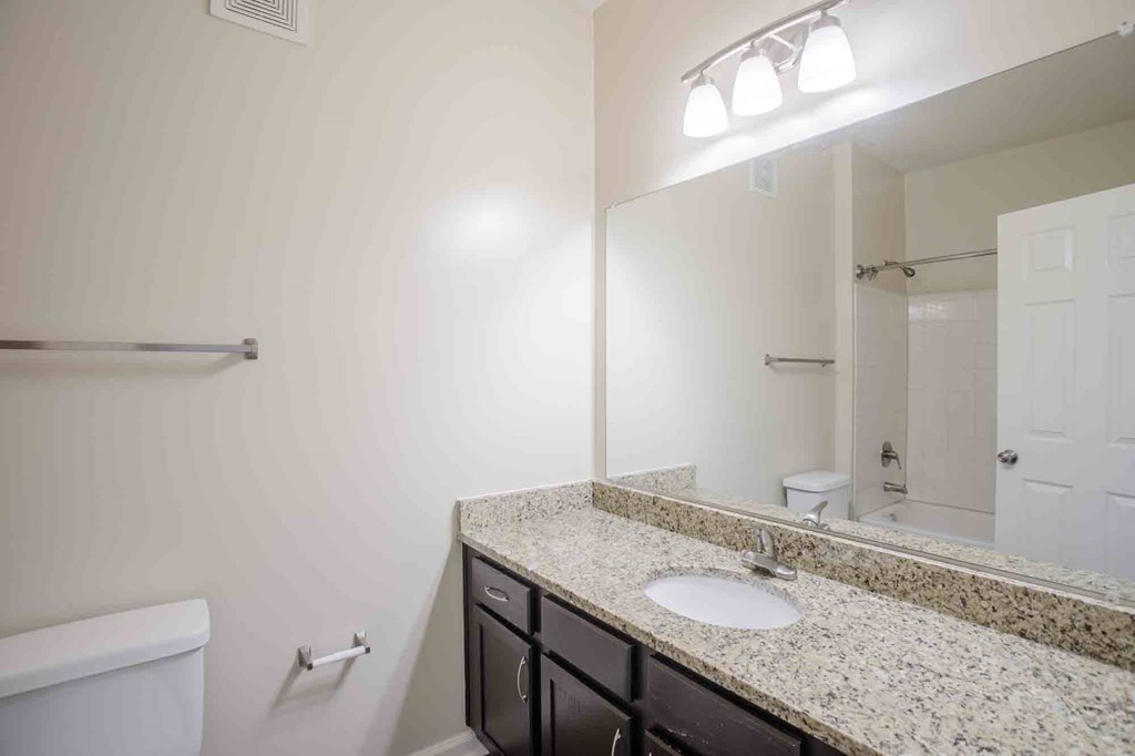 A bathroom with a large vanity, a sink, and mirror.
