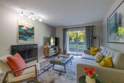 A living room with a fireplace, a chair, a couch, and a painting on the wall.