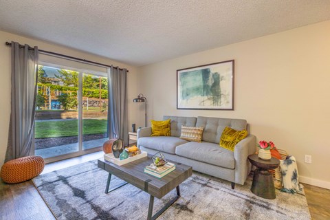 A living room with a grey couch, a coffee table, and a painting on the wall.