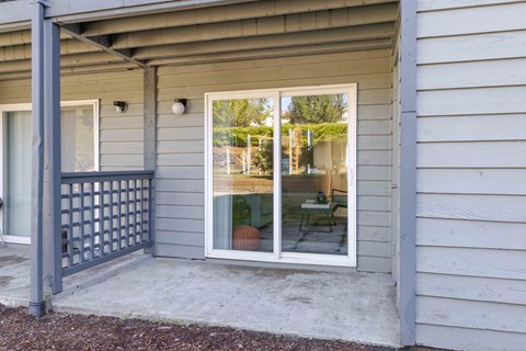A patio with a sliding glass door and a grey railing.