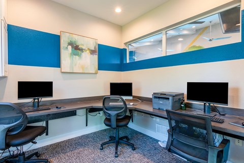 two desks with computers and chairs in a room with a window