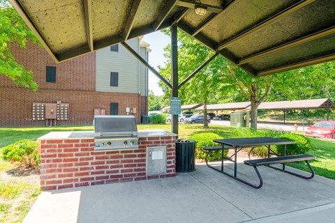 a covered patio with a barbecue grill and a picnic table