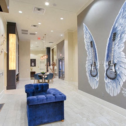 a lobby with a blue chair and a mural of two guitars