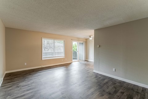 the living room and dining room of an empty home with wood flooring