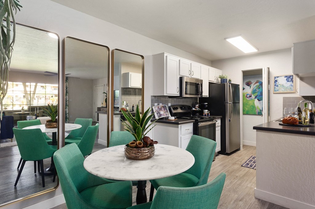 a kitchen and dining area with green chairs and a marble table