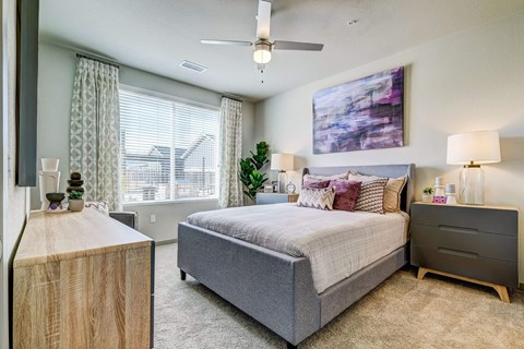 A bedroom with a bed, nightstand, and a painting on the wall.