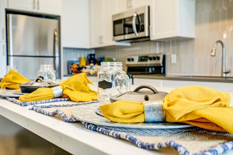 A kitchen counter with a blue and white placemat, a yellow napkin, and a silver container.