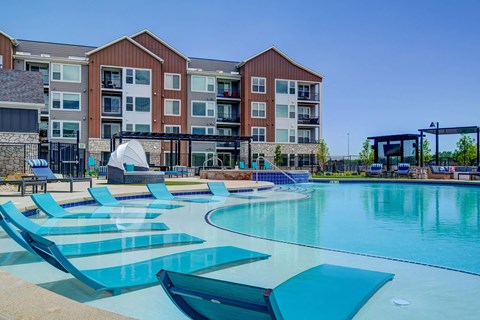 A large swimming pool with lounge chairs and a building in the background.