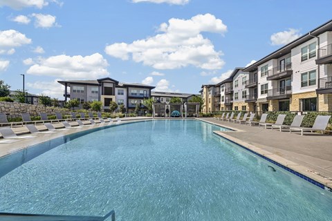 A large swimming pool in front of apartment buildings.