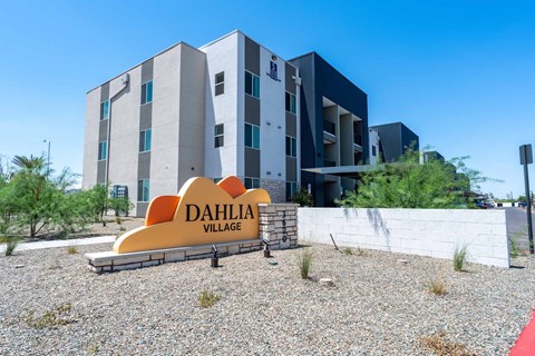 A modern building with the name Dahlia Village on a sign in front of it.