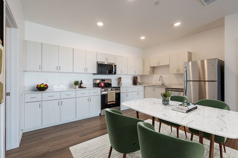 A kitchen with white cabinets and a marble table.