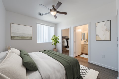 A bedroom with a bed, a ceiling fan, and a doorway leading to another room.