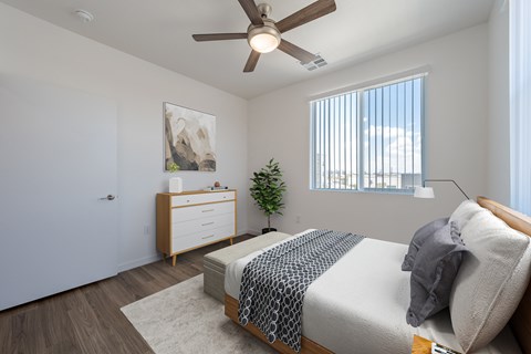 A bedroom with a bed, dresser, and a ceiling fan.