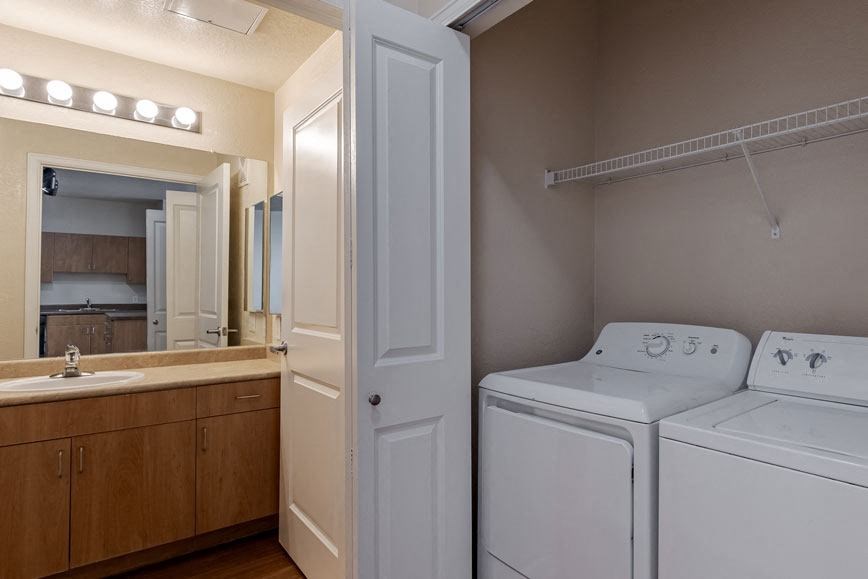 a white washer and dryer in a room with a sink and a mirror