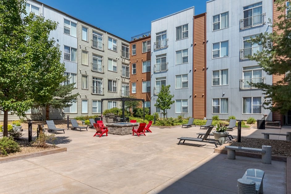 an open courtyard with benches and tables in front of an apartment building