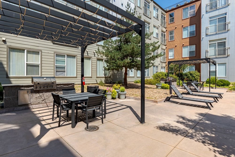a patio with a table and chairs in front of an apartment building