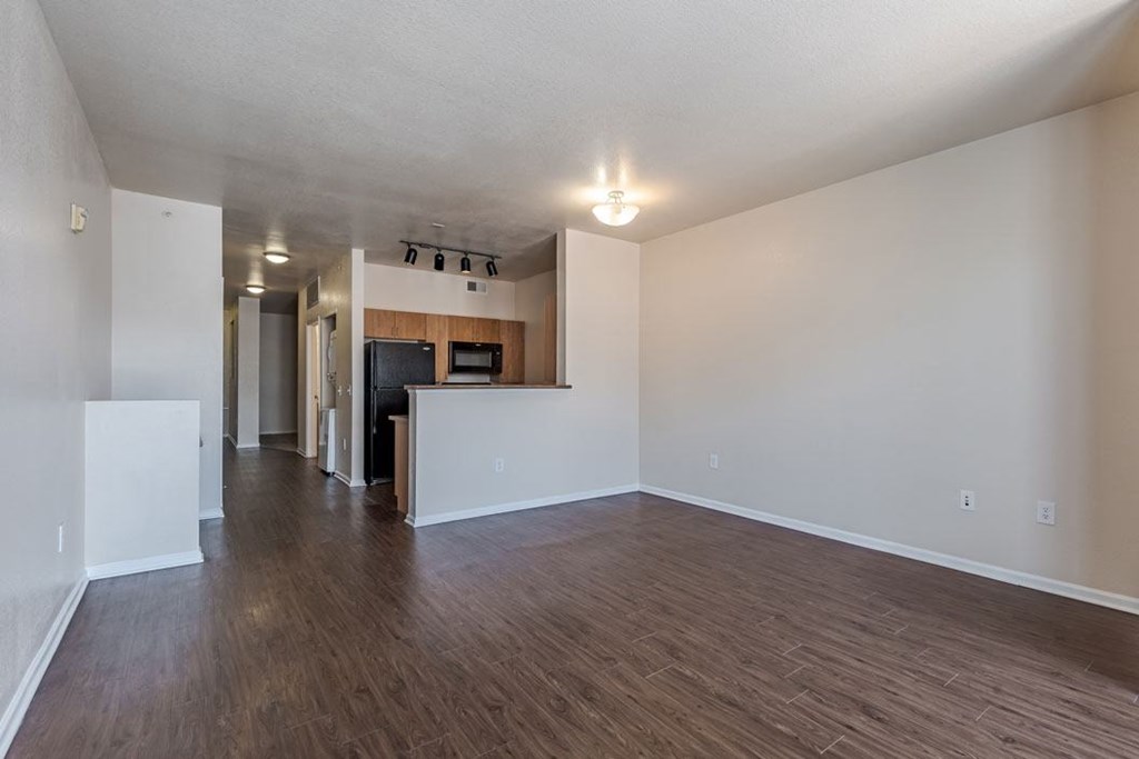 an empty living room and kitchen with a wood floor