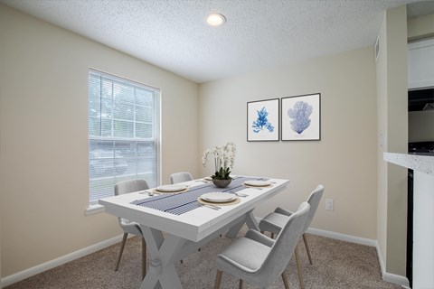 A dining room with a white table and chairs.