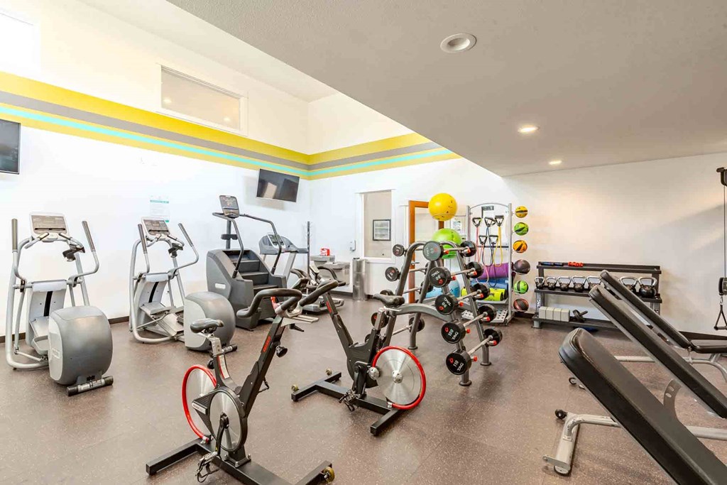 A gym with a variety of exercise equipment including treadmills, stationary bikes, and weight machines.