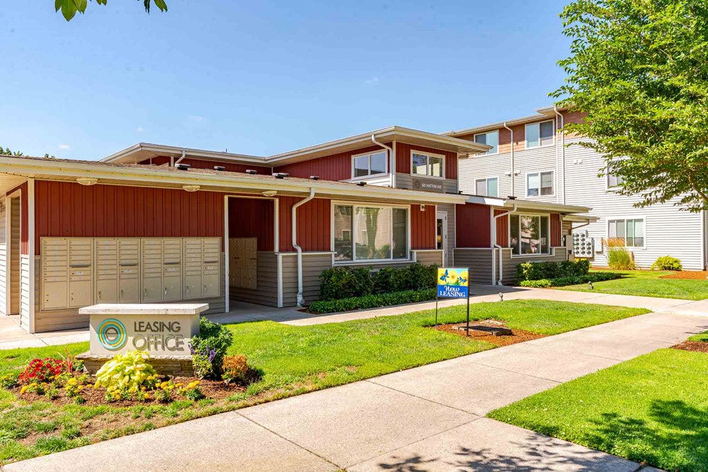 A leasing office sign is in front of a building with a red and white exterior.