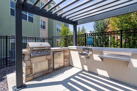 an outdoor kitchen with a grill and two sinks and a pergola