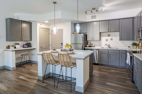 a kitchen with gray cabinets and a white island with two stools