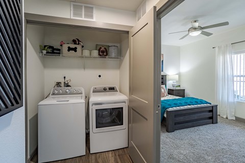 a laundry room with a washer and dryer and a bedroom with a bed