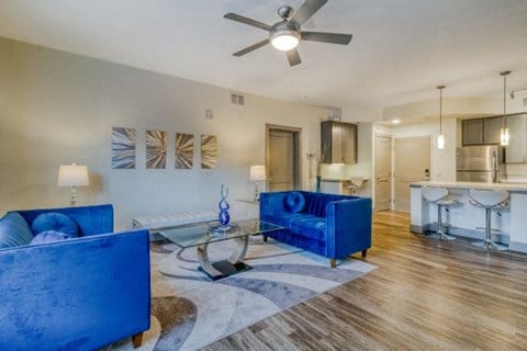 a living room with blue furniture and a ceiling fan