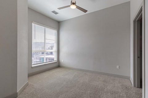 an empty living room with a window and a ceiling fan