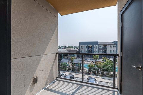 a balcony with a view of a pool and buildings in the distance