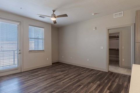 an empty living room with a ceiling fan and a door to a closet