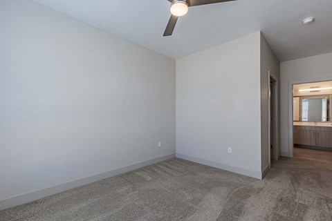 an empty living room with white walls and a ceiling fan