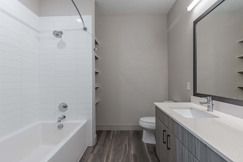 renovated bathroom with tub sink toilet and mirror at the district flats apartments