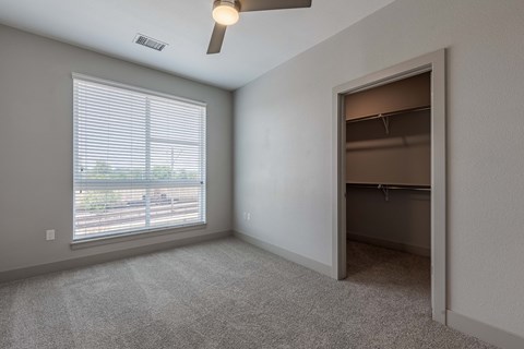 an empty living room with a large window and a closet