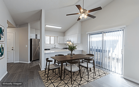A dining room with a table and chairs and a ceiling fan.